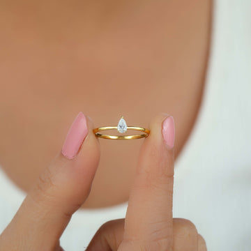 a person holding pear shape engagement ring